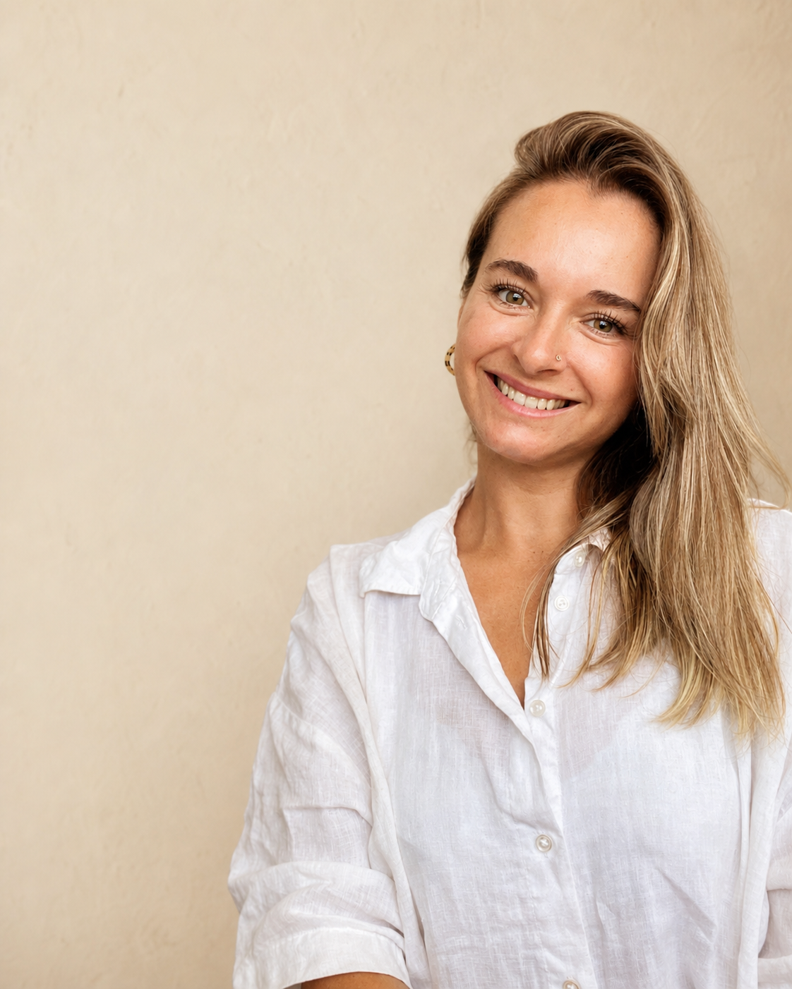 Retrato de Daniela Barraza con sonrisa abierta, fondo crema.